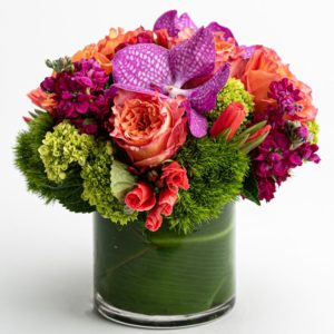 purple orchid with orange red and green florals in a vase