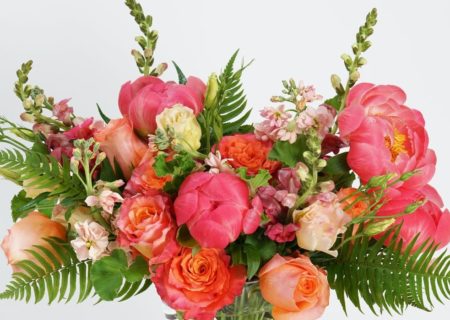 a unique collection of seasonal blooms including our "coral reef" roses, orange snap dragon, peach lisianthus, and our ever-popular coral peonies. Designed in a clear glass vase and accented with textural greens
