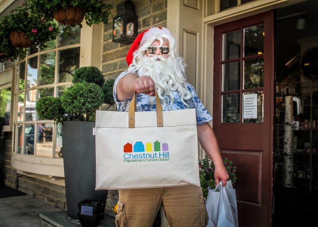 Santa strolling down street with shoppingn bag in sunglasses and tropical shirt